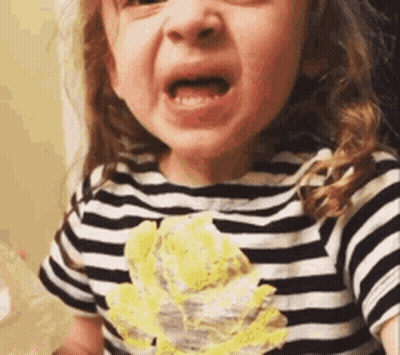 A Little Girl Wearing A Striped Shirt With A Yellow Flower On It Is Making A Funny Face . GIF