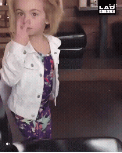 A Little Girl Wearing A White Jacket And A Purple Dress Is Giving The Middle Finger GIF