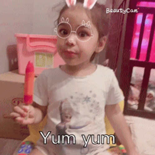 A Little Girl Wearing Glasses And Bunny Ears Is Holding A Popsicle And The Words Yum Yum Are Below Her GIF