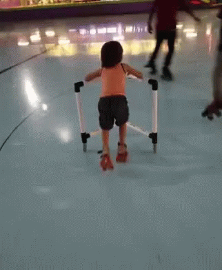 A Little Girl Wearing Roller Skates Is Walking On A Rink GIF