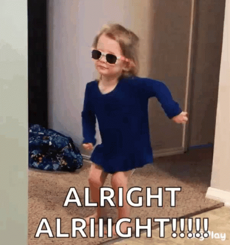 A Little Girl Wearing Sunglasses And A Blue Dress Is Dancing In A Hallway . GIF