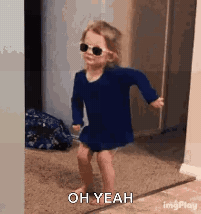 A Little Girl Wearing Sunglasses And A Blue Dress Is Dancing In A Room . GIF