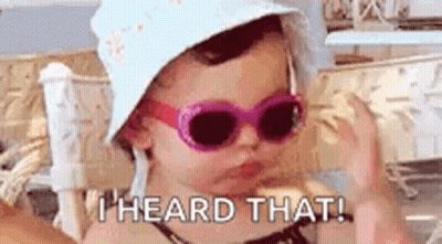 A Little Girl Wearing Sunglasses And A Hat Is Making A Funny Face . GIF