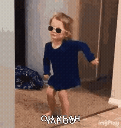 A Little Girl Wearing Sunglasses Is Dancing In A Hallway . GIF