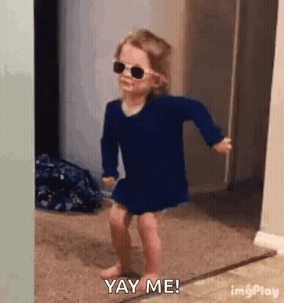 A Little Girl Wearing Sunglasses Is Dancing On The Floor . GIF