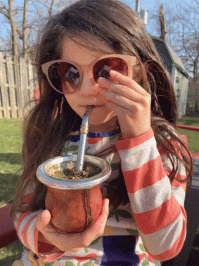 A Little Girl Wearing Sunglasses Is Drinking From A Cup GIF
