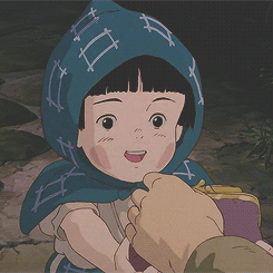 A Little Girl With A Blue Scarf Around Her Head Is Being Held By A Person GIF