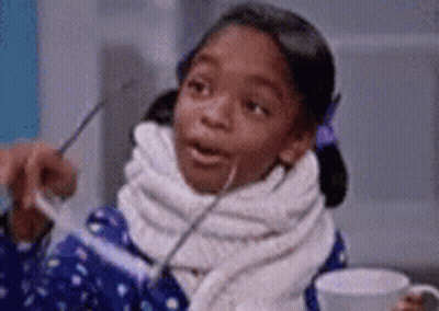 A Little Girl With A Scarf Around Her Neck Is Holding A Cup Of Coffee . GIF