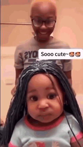 A Little Girl With A Wig On Her Head Is Standing Next To A Man . GIF