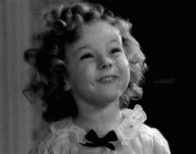 A Little Girl With Curly Hair Is Wearing A Bow Tie GIF