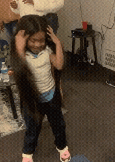 A Little Girl With Long Hair Is Dancing In A Living Room With A Woman Holding Her Hair . GIF