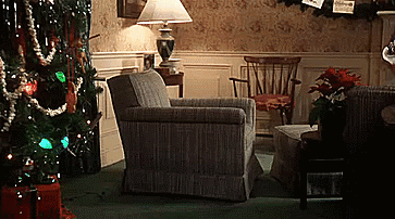 A Living Room Decorated For Christmas With A Chair A Lamp And A Christmas Tree GIF