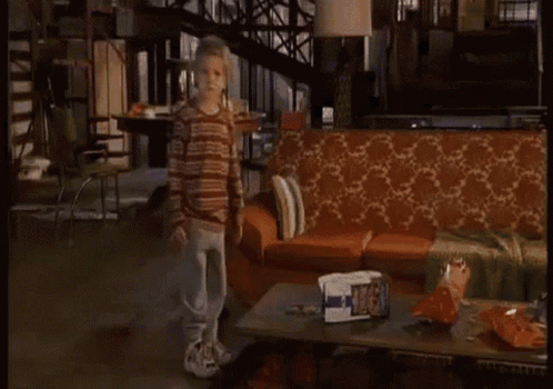 A Living Room With A Couch And A Coffee Table With A Bag Of Chips On It GIF