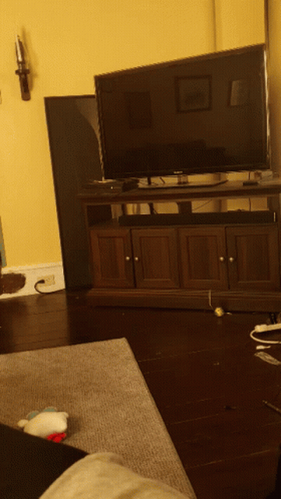 A Living Room With A Flat Screen TV On A Wooden Stand GIF