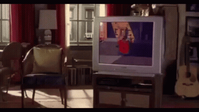 A Living Room With A Television On A Stand And A Guitar GIF