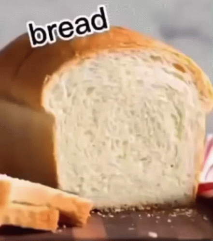 A Loaf Of Bread Is Sitting On Top Of A Wooden Table . GIF