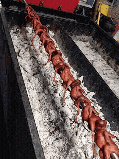 A Long Row Of Chickens Are Cooking On A Grill GIF
