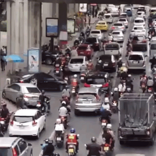 A Lot Of Cars And Motorcycles Are Driving Down The Street GIF