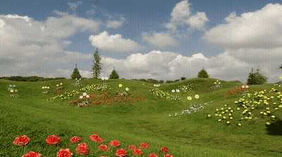 A Lush Green Field With Flowers And Trees In The Background GIF