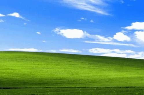 A Lush Green Hillside With A Blue Sky And White Clouds GIF