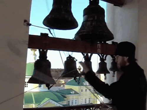 A Man Adjusts A Bell With The Letter L On The Bottom GIF