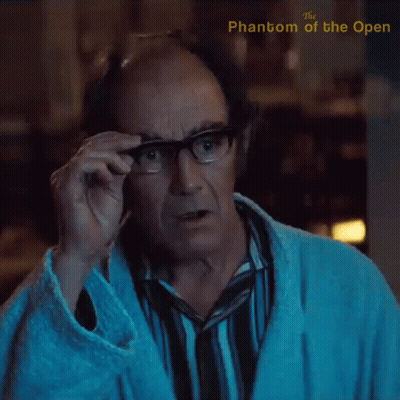 A Man Adjusts His Glasses With The Phantom Of The Open Written On The Bottom GIF
