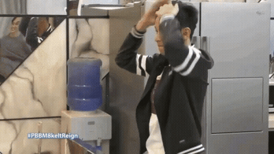 A Man Adjusts His Hair In Front Of A Water Dispenser With The Hashtag #Pbbm8keltreign GIF