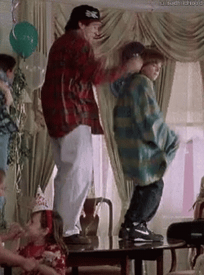 A Man And A Boy Are Dancing In A Living Room . GIF