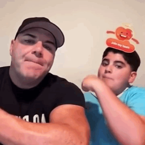 A Man And A Boy Are Posing For A Picture Together . The Boy Is Wearing A Pumpkin Headband . GIF