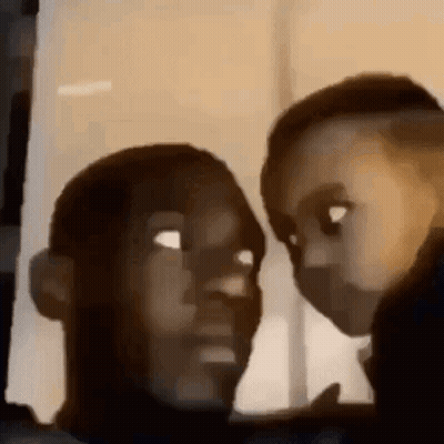 A Man And A Child Are Looking At Each Other In A Dark Room . GIF