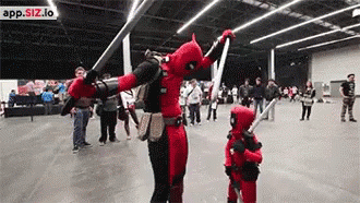 A Man And A Child Dressed In Deadpool Costumes Are Dancing In A Crowded Room . GIF
