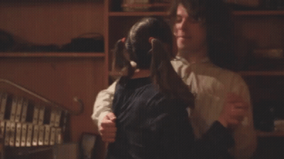 A Man And A Girl Are Hugging In Front Of A Bookshelf GIF