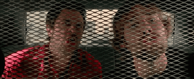 A Man And A Woman Are Behind A Mesh Fence GIF