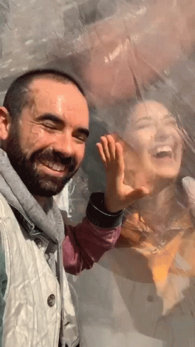 A Man And A Woman Are Behind A Plastic Bubble And The Man Is Smiling GIF