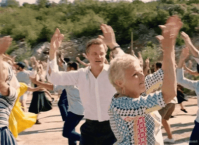 A Man And A Woman Are Dancing In A Crowd With Their Arms In The Air . GIF
