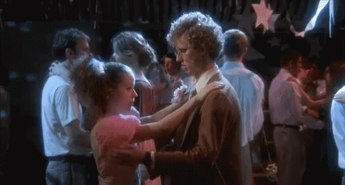 A Man And A Woman Are Dancing In A Crowded Room At A Party . GIF