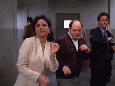 A Man And A Woman Are Dancing In A Hallway With Other People . GIF
