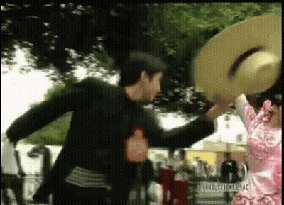 A Man And A Woman Are Dancing In A Park While Holding Hats . GIF