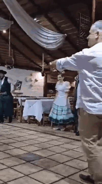 A Man And A Woman Are Dancing In A Room While A Man Plays A Guitar . GIF