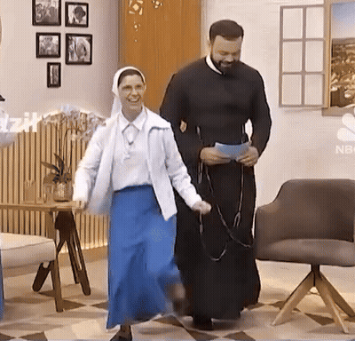 A Man And A Woman Are Dancing In A Room With A Nbc Logo On The Wall GIF