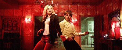 A Man And A Woman Are Dancing In A Room With Red Walls . GIF