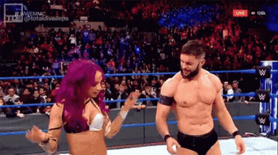 A Man And A Woman Are Dancing In A Wrestling Ring While A Crowd Watches . GIF