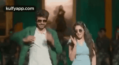 A Man And A Woman Are Dancing In Front Of A Crowd . GIF