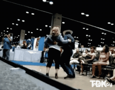 A Man And A Woman Are Dancing In Front Of A Crowd That Is Watching .. GIF