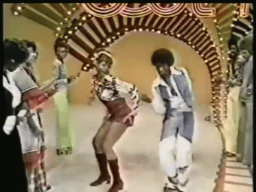 A Man And A Woman Are Dancing In Front Of A Group Of People GIF
