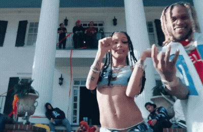 A Man And A Woman Are Dancing In Front Of A Large Building GIF