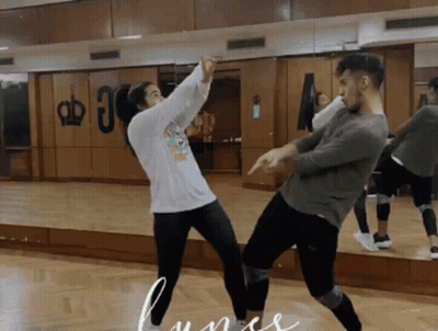 A Man And A Woman Are Dancing In Front Of A Mirror With A Crown On The Wall Behind Them GIF