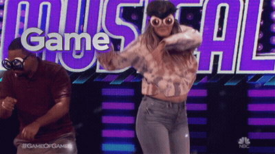 A Man And A Woman Are Dancing In Front Of A Screen That Says Game Of Games GIF