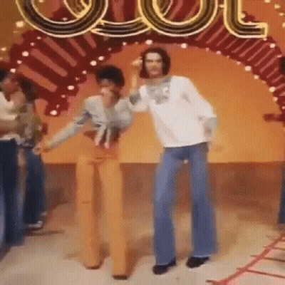 A Man And A Woman Are Dancing In Front Of A Sign That Says ' Cool ' GIF