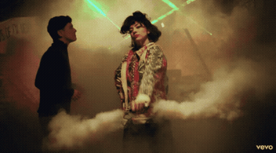 A Man And A Woman Are Dancing In Front Of A Sign That Says ' Vevo ' GIF